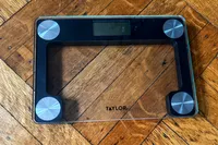 The Taylor Digital Compact Scale with Travel/Storage Tote on a wooden floor