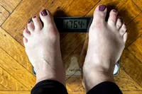 A person stands on the Taylor Digital Compact Scale with Travel/Storage Tote