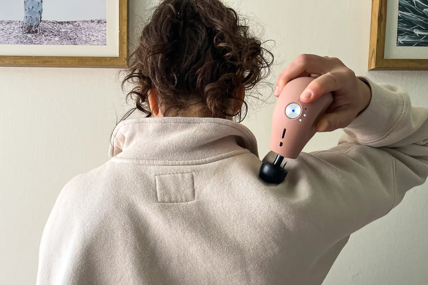 A person uses the Therabody Theragun Mini (3rd Generation) on their shoulder