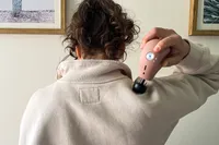 A person uses the Therabody Theragun Mini (3rd Generation) on their shoulder