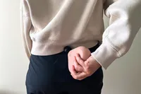 A person uses the Therabody Theragun Mini (3rd Generation) on their lower back