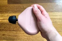 A person holds up the Therabody Theragun Mini (3rd Generation)