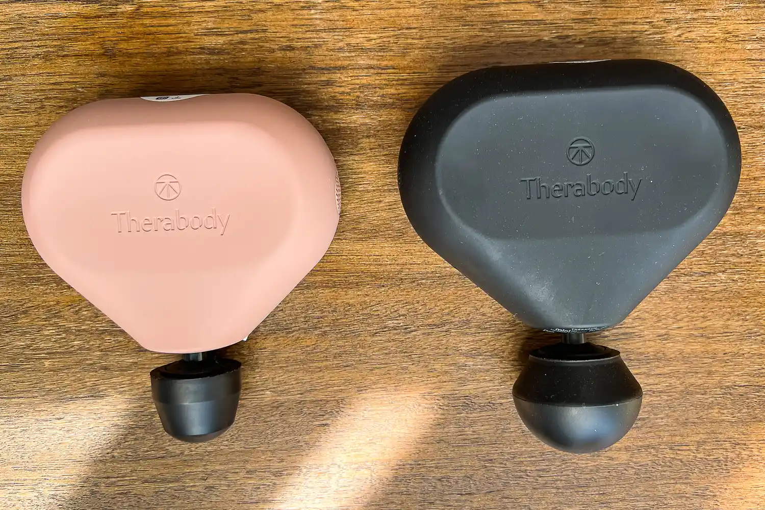 The Therabody Theragun Mini (3rd Generation) on a wooden table