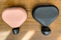 The Therabody Theragun Mini (3rd Generation) on a wooden table