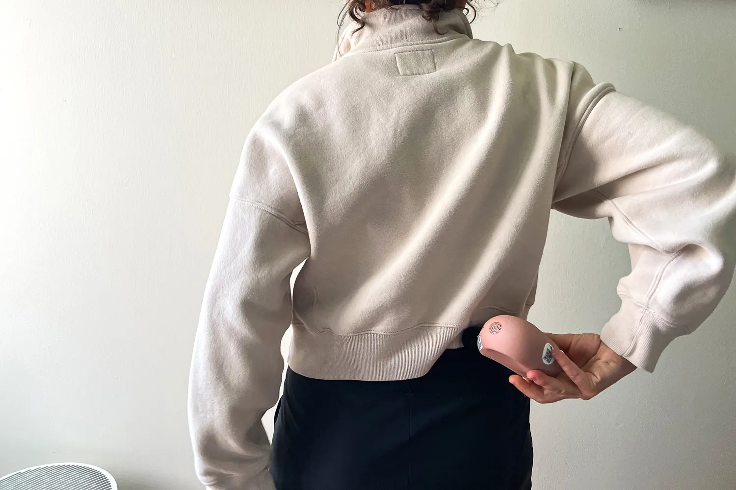 A person uses the Therabody Theragun Mini (3rd Generation) on their lower back