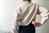 A person uses the Therabody Theragun Mini (3rd Generation) on their lower back