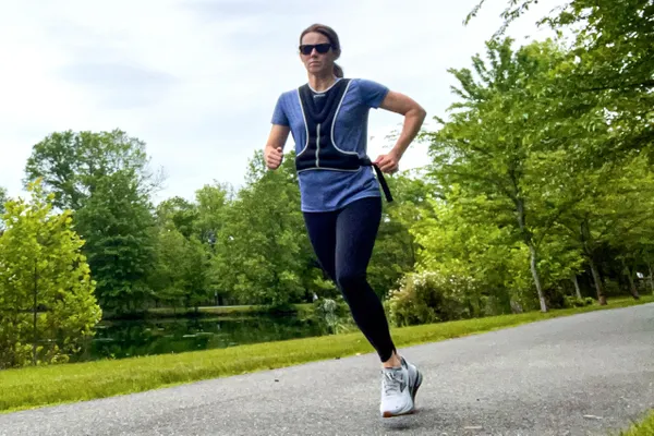 A person runs outside while wearing the Tone Fitness HHWV-TN Weighted Vest