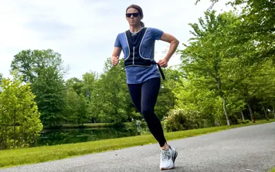 A person runs outside while wearing the Tone Fitness HHWV-TN Weighted Vest