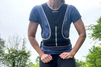 A person stretches while wearing the Tone Fitness HHWV-TN Weighted Vest