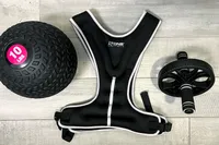 The Tone Fitness HHWV-TN Weighted Vest next to a medicine ball and ab roller