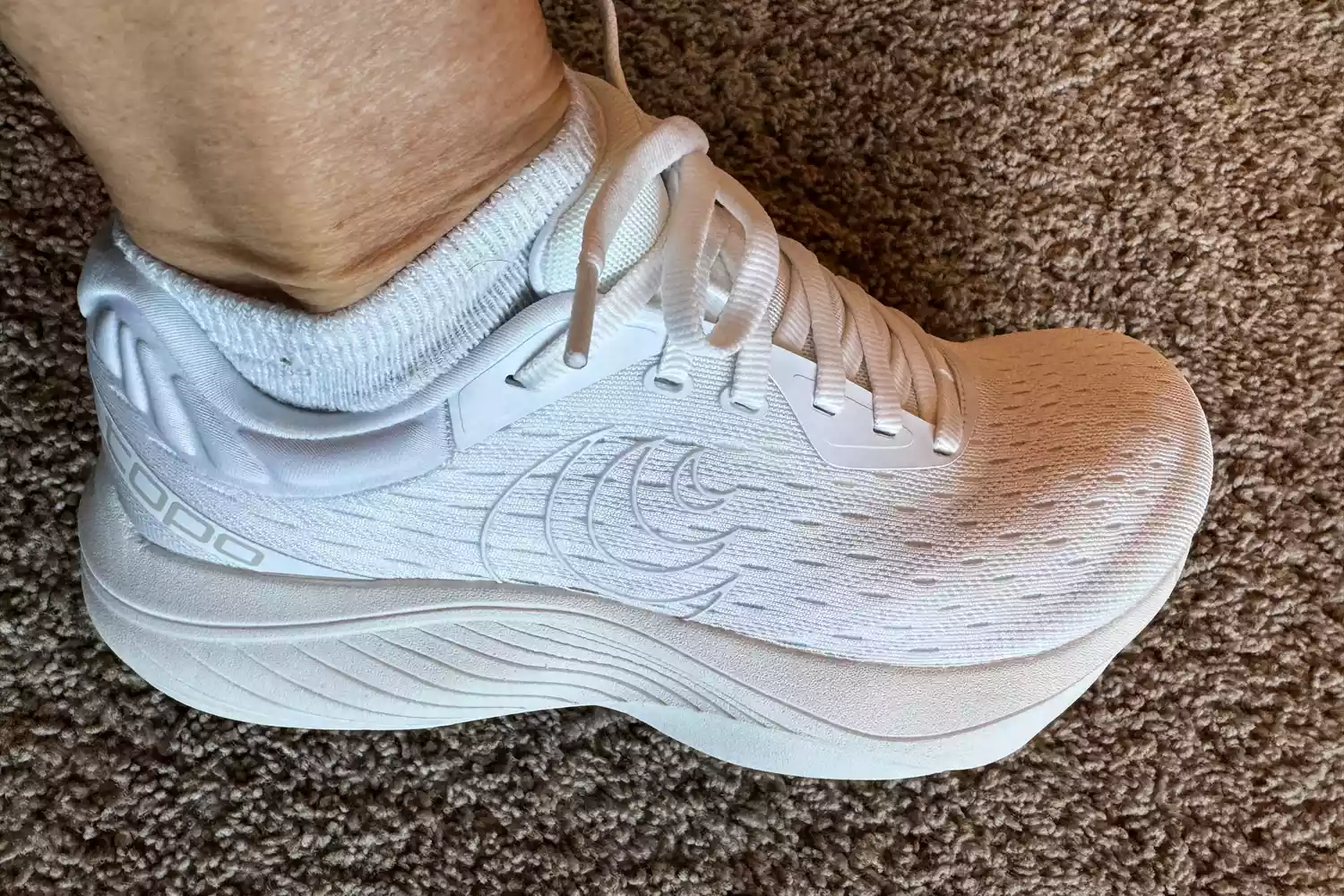 A person wears the Topo Athletic Women's Atmos Running Shoes inside on carpet