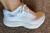 A person wears the Topo Athletic Women's Atmos Running Shoes inside on carpet