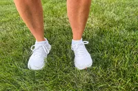A person stands in grass while wearing the Topo Athletic Women's Atmos Running Shoes