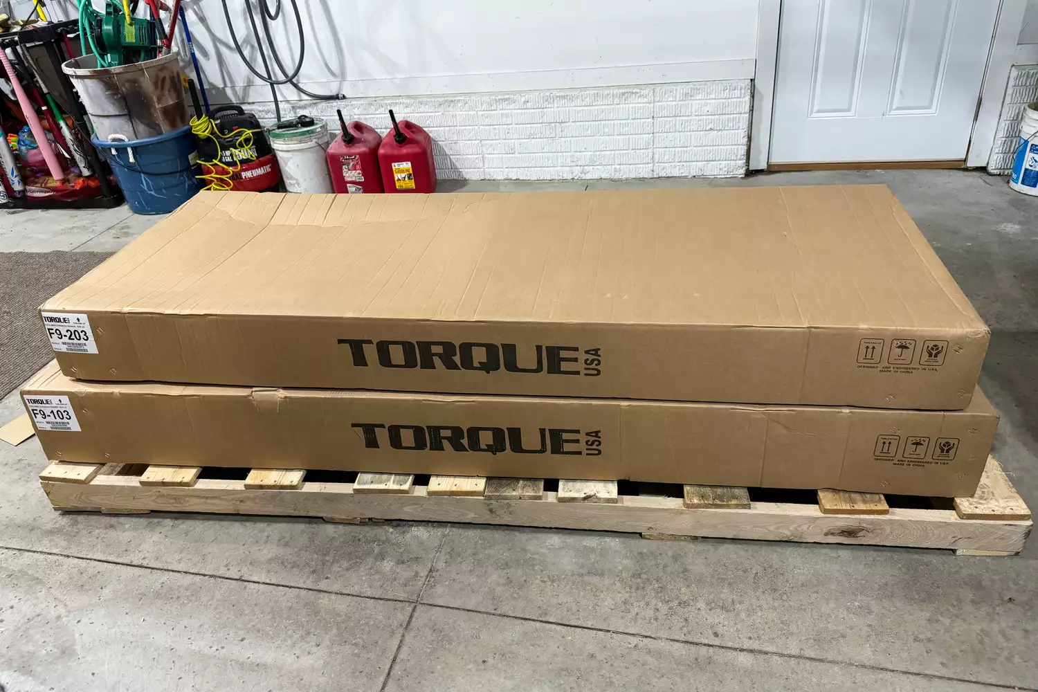 The pieces of the Torque Fitness' Free-Standing F9 Fold Away Functional Trainer in cardboard packaging