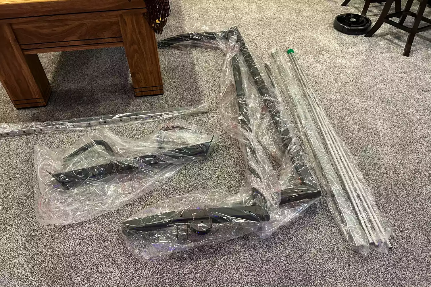 The unassembled components of the Torque Fitness Free-Standing F9 Fold Away Functional Trainer on a carpet