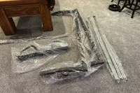 The unassembled components of the Torque Fitness Free-Standing F9 Fold Away Functional Trainer on a carpet