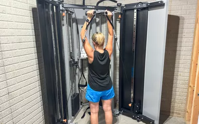 A person exercises on the dual adjustable cable pulleys of the Torque Fitness Free-Standing F9 Fold Away Functional Trainer