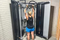 A person exercises on the dual adjustable cable pulleys of the Torque Fitness Free-Standing F9 Fold Away Functional Trainer