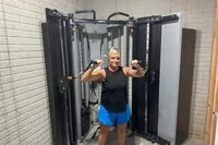 A person uses the Torque Fitness Free-Standing F9 Fold Away Functional Trainer's swivel pulleys for exercise
