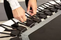 Person adjusting the spring strap buckle on an Acon 55in Trampoline Hexagon