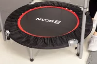 Person standing next to a BCAN Foldable Mini Trampoline surrounded by padded mats