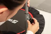 Person tighting screw on handle bar for a BCAN Foldable Mini Trampoline