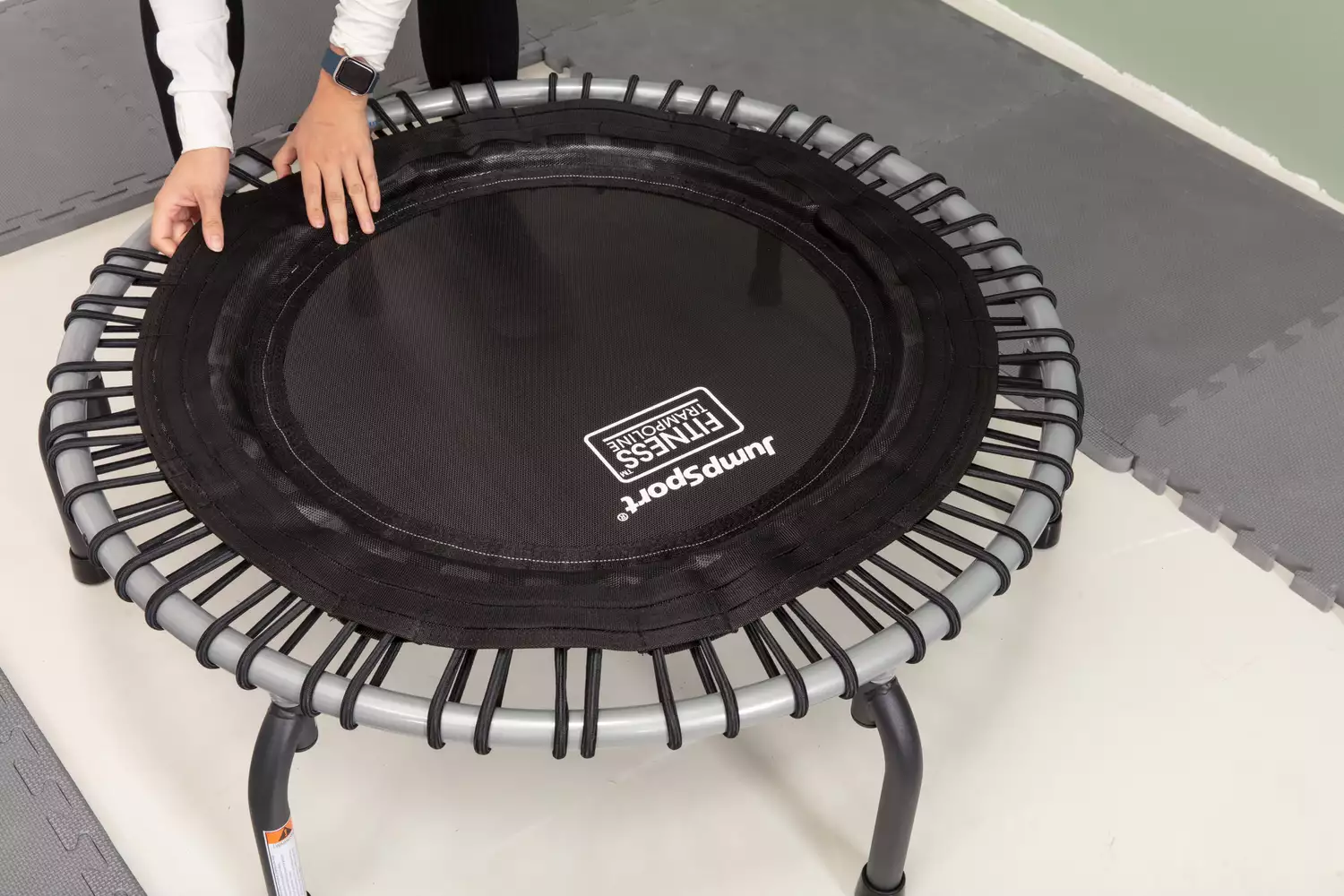 Person lifting up the outer seam of a JumpSport 350 Indoor Fitness Trampoline 