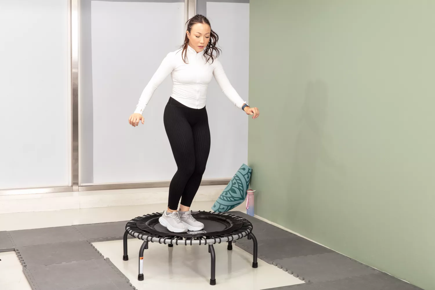 Person jumping on a JumpSport 350 Indoor Fitness Trampoline surrounded by padded mats