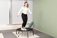 Person jumping on a JumpSport 350 Indoor Fitness Trampoline surrounded by padded mats
