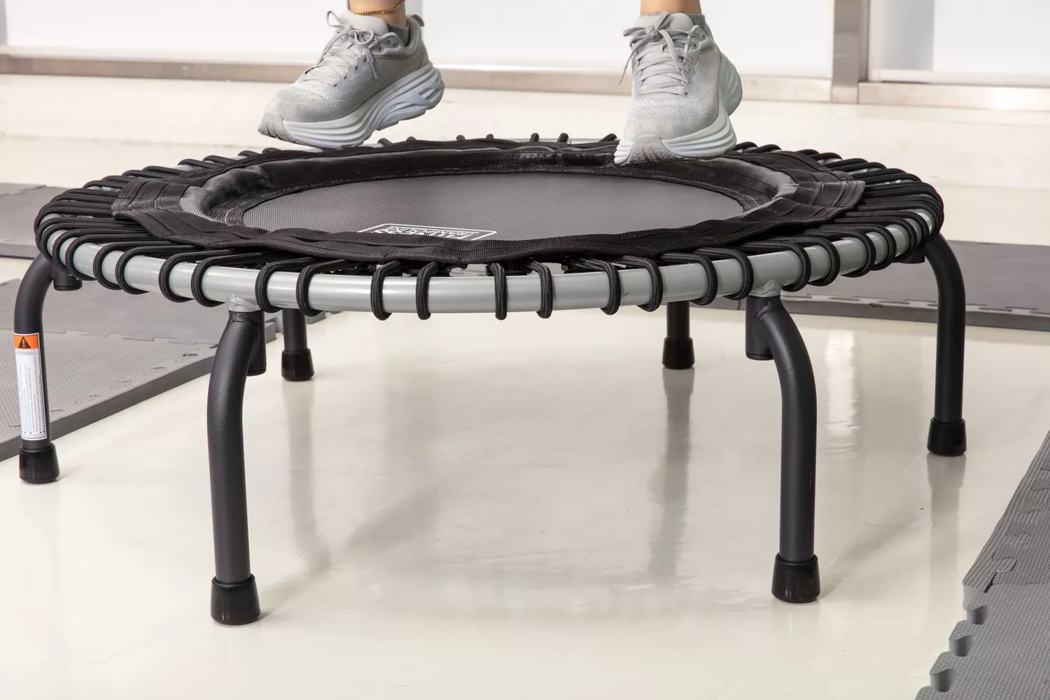 Person jumping on JumpSport 350 Indoor Fitness Trampoline surrounded by padded mats