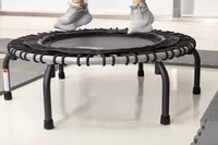 Person jumping on JumpSport 350 Indoor Fitness Trampoline surrounded by padded mats