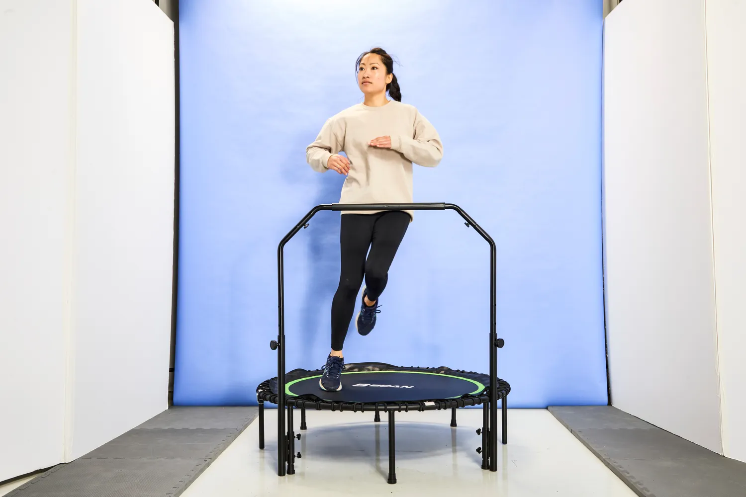 A person using the BCAN 450/550 Lbs Foldable Mini Trampoline in front of a blue backdrop