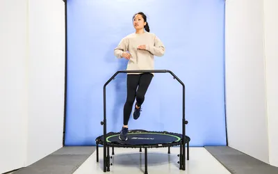 A person using the BCAN 450/550 Lbs Foldable Mini Trampoline in front of a blue backdrop