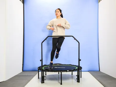 A person using the BCAN 450/550 Lbs Foldable Mini Trampoline in front of a blue backdrop
