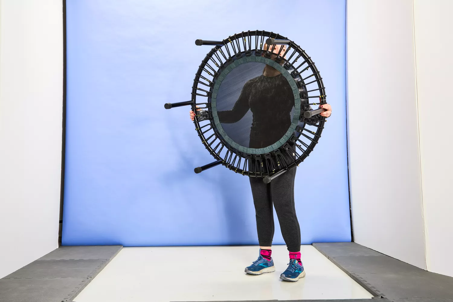 A person lifting the bellicon 39 Inch Mini Trampoline in front of a blue background