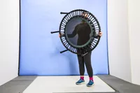 A person lifting the bellicon 39 Inch Mini Trampoline in front of a blue background