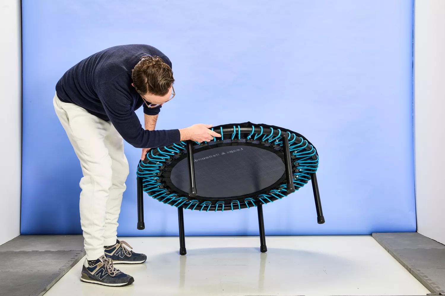 A person lifting up the Leaps and Rebounds Mini Fitness Trampoline and Rebounder to look at the bottom