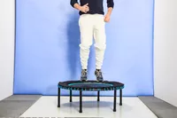 A person jumping on the Leaps and Rebounds Mini Fitness Trampoline and Rebounder in front of a blue wall