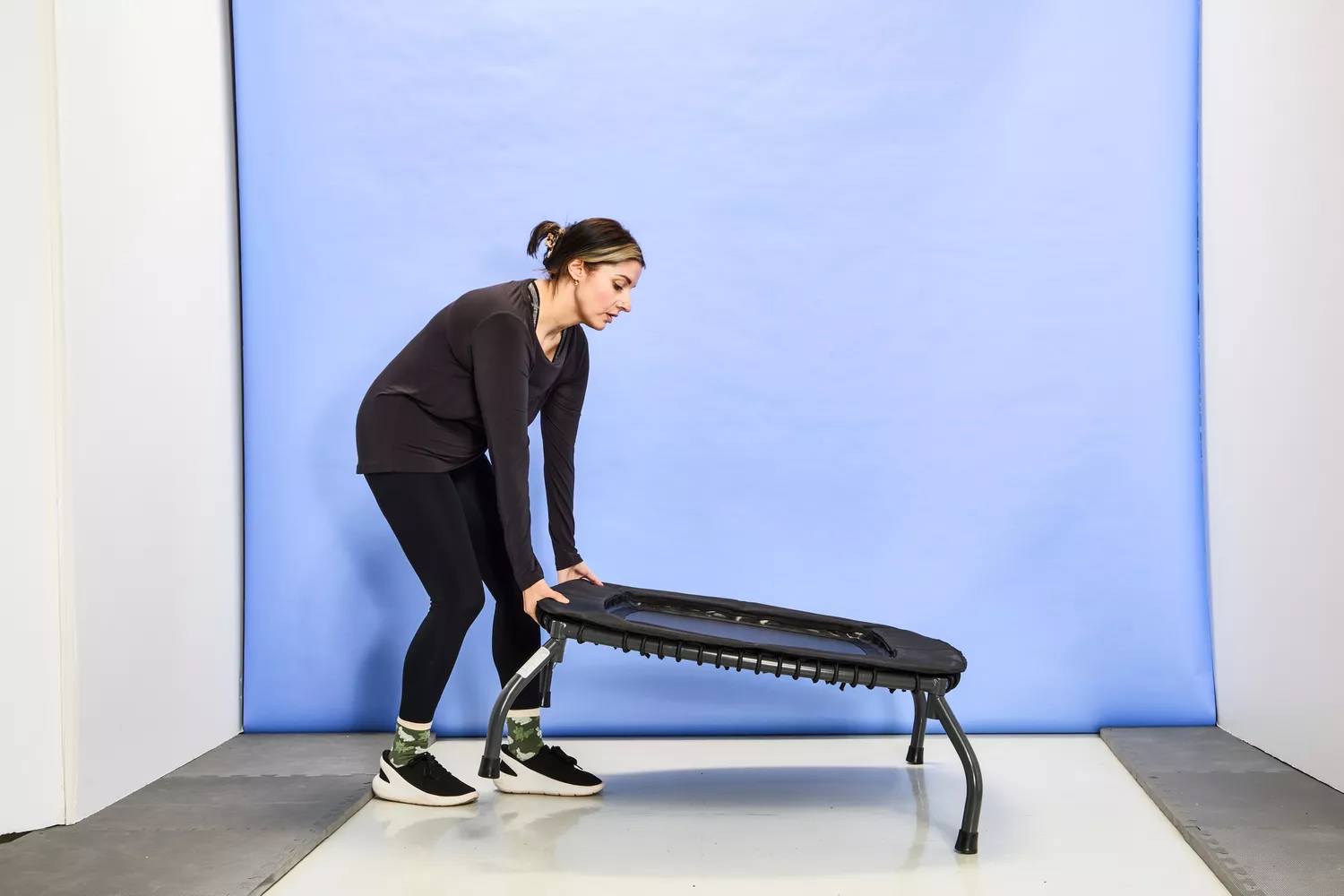 A person slightly lifting the Sunny Health & Fitness 36 Inch Indoor & Outdoor Exercise Trampoline off of the ground