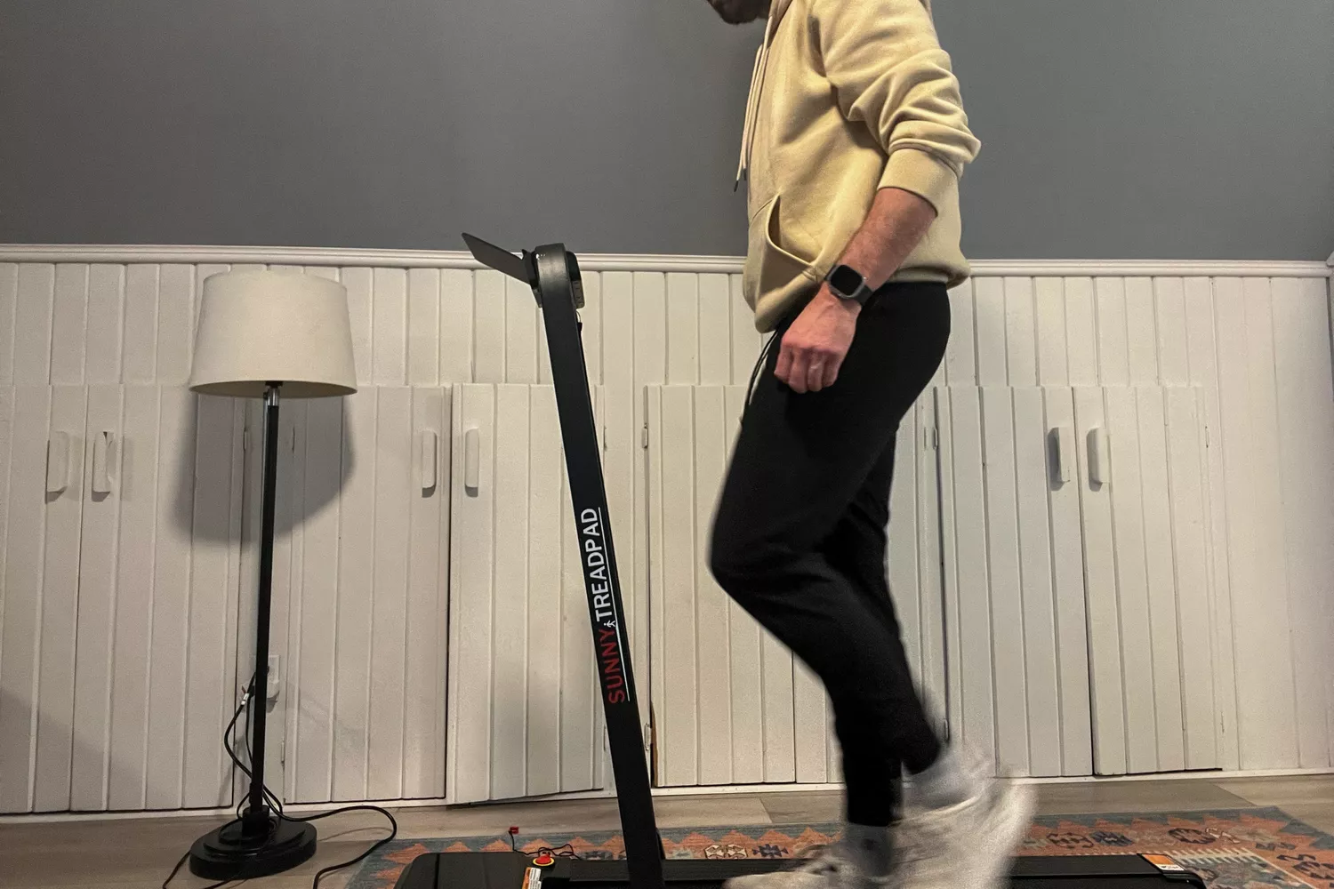 A person walks on the Sunny Health & Fitness Pacer Smart Compact Auto Incline Treadpad Treadmill