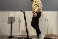 A person walks on the Sunny Health & Fitness Pacer Smart Compact Auto Incline Treadpad Treadmill