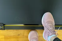 A person wearing sneakers steps onto the UREVO Walking Pad Under Desk Treadmill