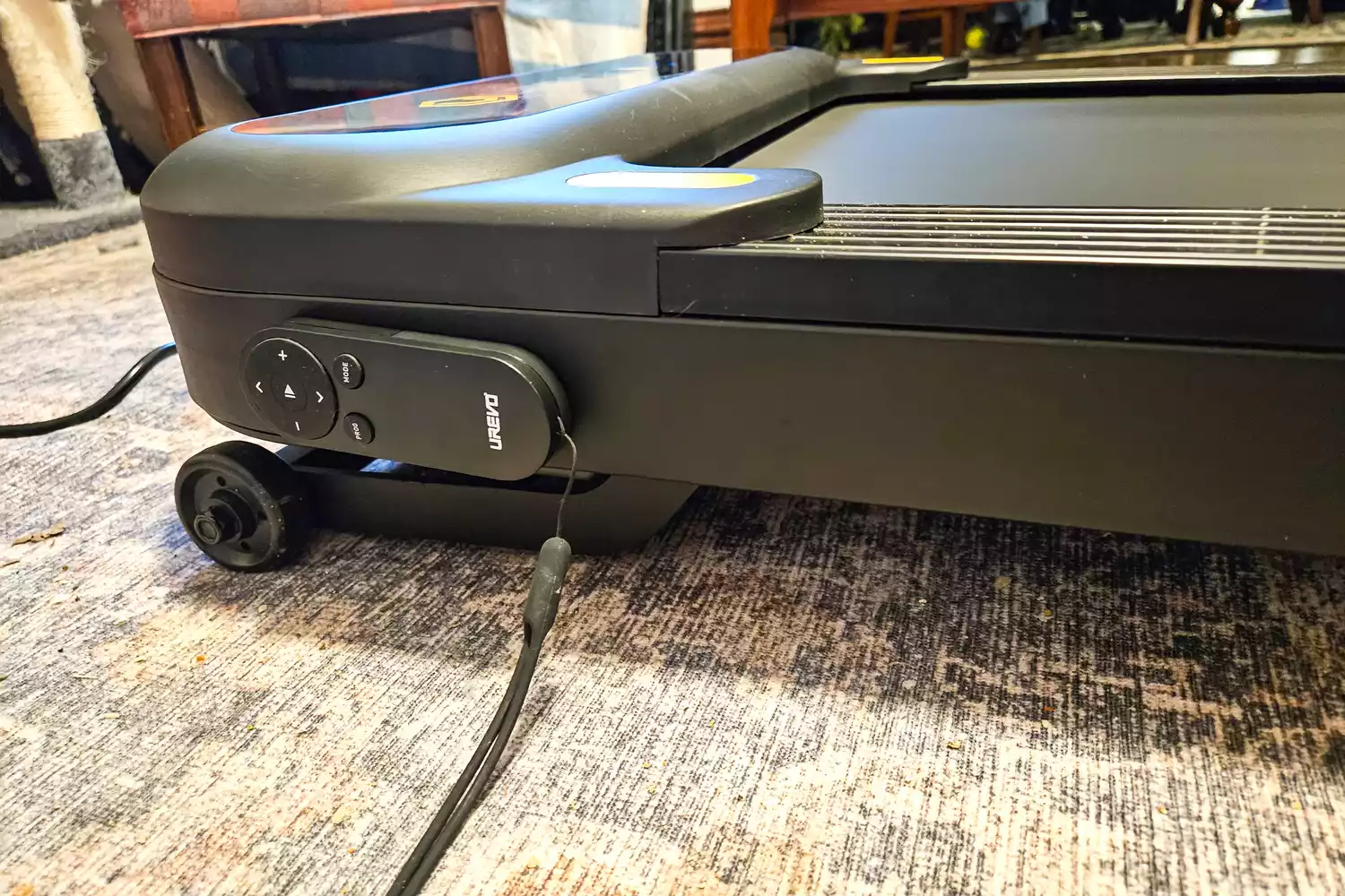 The remote control for the Urevo SpaceWalk 3S Treadmill attached to the base