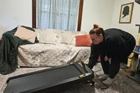 A person sets the Urevo SpaceWalk 3S Treadmill in place on a rug