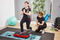 A person does lunges on the Hurtle Fitness Vibration Platform Machine