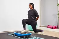 A person does lunges on the LifePro Rumblex Plus 4D Vibration Plate Exercise Machine