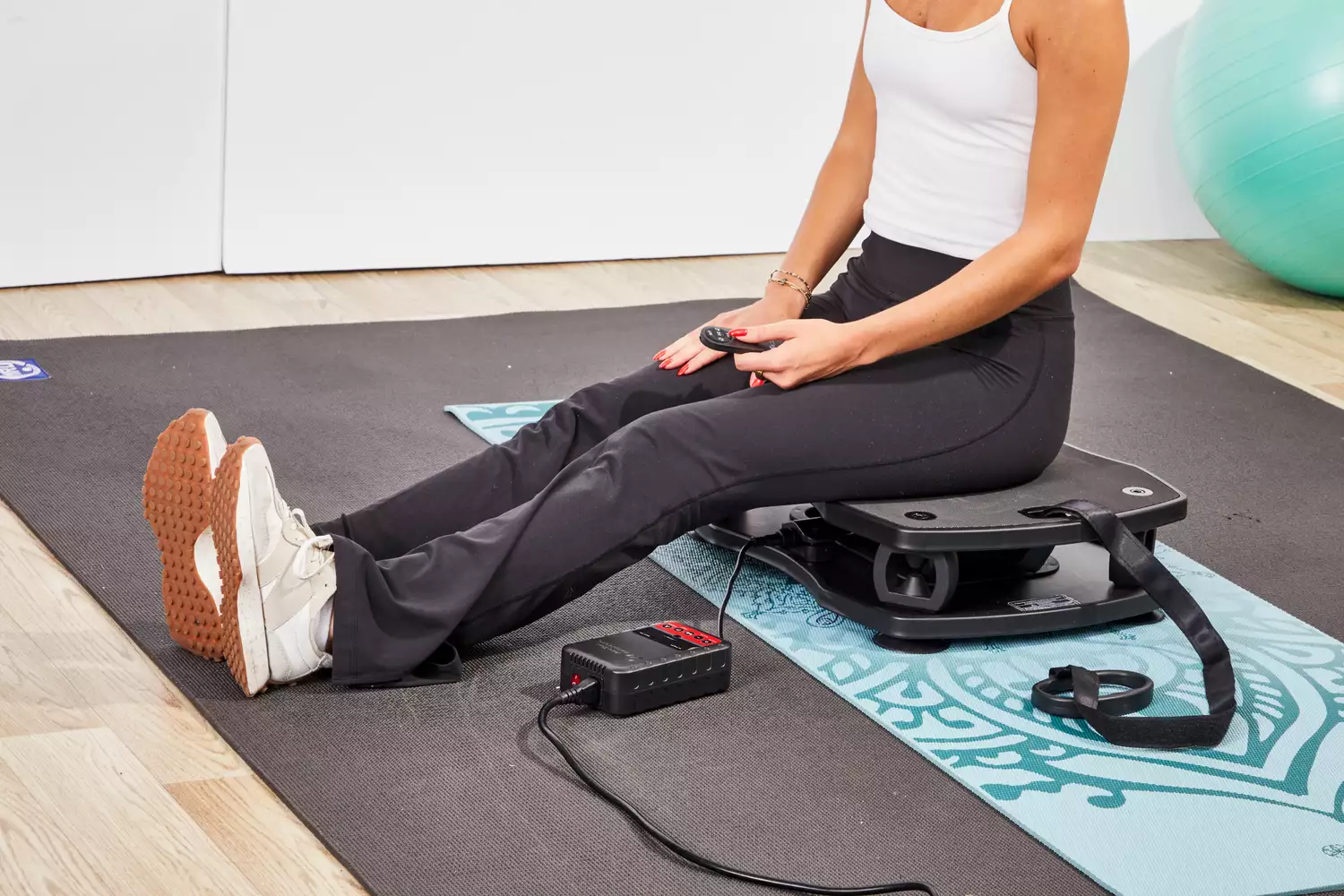 A person sits on the VT Vibration Therapeutic Frequency Vibration Plate