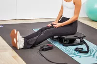 A person sits on the VT Vibration Therapeutic Frequency Vibration Plate