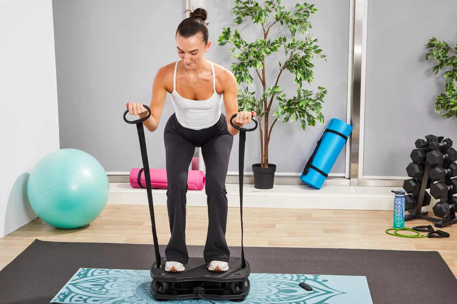 A person pulls the resistance bands on the VT Vibration Therapeutic Frequency Vibration Plate