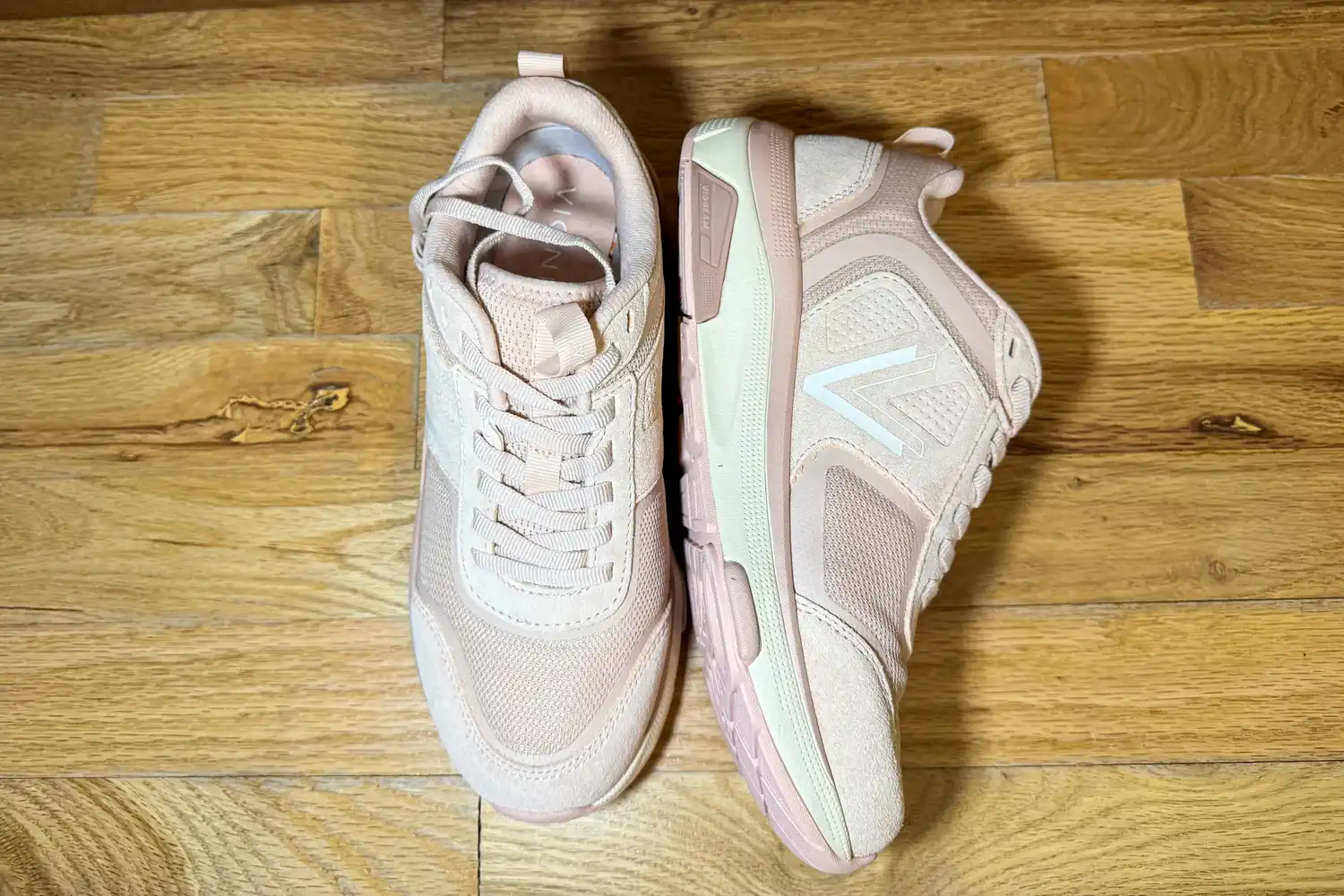 A pair of Vionic Women's Walk Strider Sneakers on a wooden floor